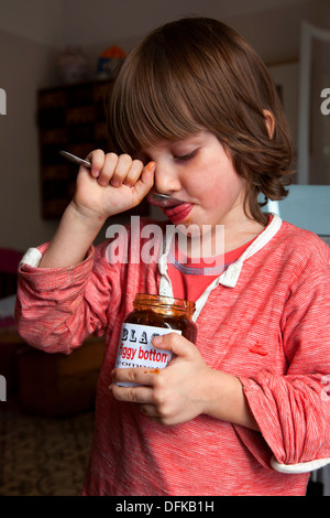 Four and a half year old boy eating fig compote from a jar with spoon. Stock Photo