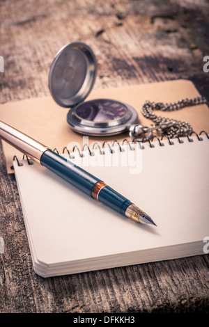 Vintage ink pen and pocket watch on notebook Stock Photo