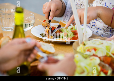 Midsection of woman cutting piece of meat on plate at table Stock Photo