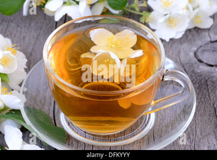 Cup of herbal tea with jasmine flowers on wooden table Stock Photo