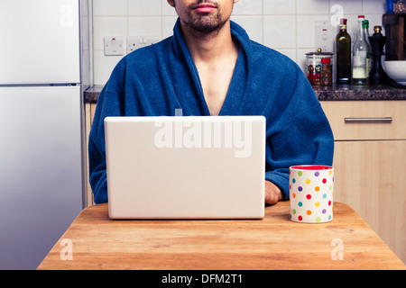 Young man using laptop in kitchen Stock Photo