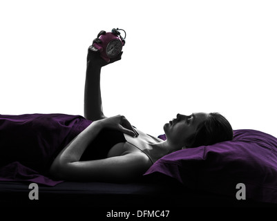 one woman in bed looking at alarm clock silhouette studio on white background Stock Photo