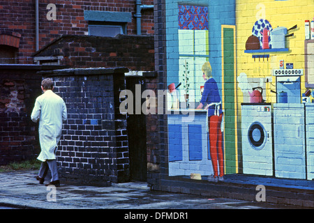 Man walking past wall mural INSIDE OUT HOUSE on the gable end of a Rochdale House Lancashire UK 1975 KATHY DEWITT Stock Photo