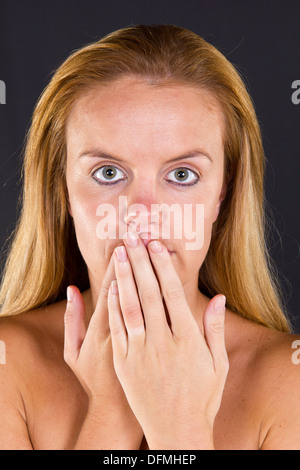 A young woman covering her mouth with her hands The three wise monkeys.  See no evil, see no evil, speak no evil Stock Photo