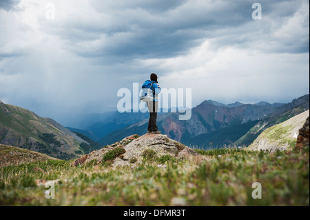 Female hiker watches approaching thunderstorms from Ice Lakes Basin, San Juan mountains, Colorado, USA Stock Photo