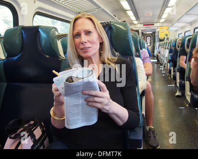 Woman perusing job listings on a commuter train from the suburbs into New York City, New York, USA Stock Photo