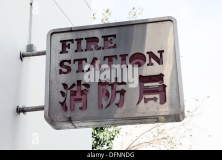 It's a photo of the exit or the doors of a fire station sign or board sign against a wall. It's in English and Chinese language Stock Photo