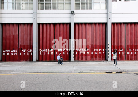 It's a photo of the exit or the doors of a fire station in a city. It's in Hong Kong. The doors are closed and kids plays Stock Photo