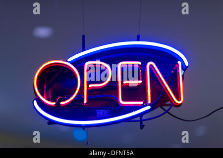 Neon OPEN sign in store window, glowing purple red orange Stock Photo