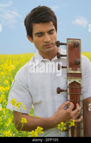 Close-up of a man playing sitar in a mustard field Stock Photo