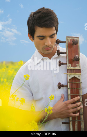 Close-up of a man playing sitar in a mustard field Stock Photo