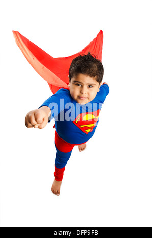 Boy dressed as a superman standing with his hand raised Stock Photo