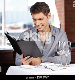 Smiling man looking at the drinks menu in a restaurant Stock Photo
