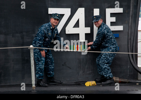 Master Chief Machinist's Mate Perry Willis, Ohio-class ballistic missile submarine USS Maine’s (SSBN 741) gold crew chief of boat, and Senior Chief Electrician Technician Jon Miller, USS Maine blue crew chief of the boat, place the Meritorious Unit Commen Stock Photo