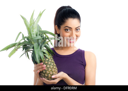Portrait of a woman holding a pineapple and smiling Stock Photo