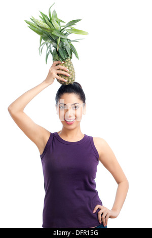 Portrait of a woman carrying a pineapple on her head and smiling Stock Photo