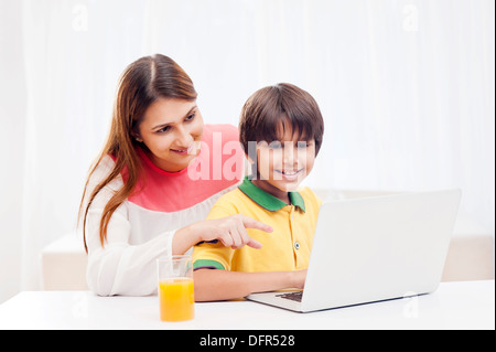 Boy using a laptop with his mother Stock Photo