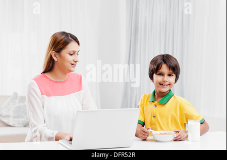 Woman using a laptop with her son having breakfast Stock Photo