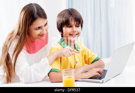 Boy using a laptop with his mother sitting behind him Stock Photo