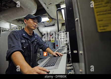 Gas Turbine Systems Technician (Mechanical) 3rd Class Russel Kates, assigned to the Ticonderoga-class guided-missile cruiser USS Antietam (CG 54), monitors a control console in one of the ship's main engine spaces. Antietam is on patrol with the George Wa Stock Photo