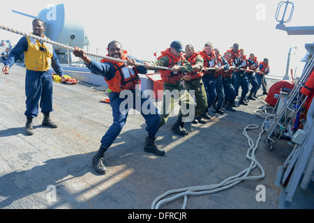 Sailors aboard the guided-missile destroyer USS Ramage (DDG 61) heave a line during a man overboard drill. Ramage, homeported i Stock Photo
