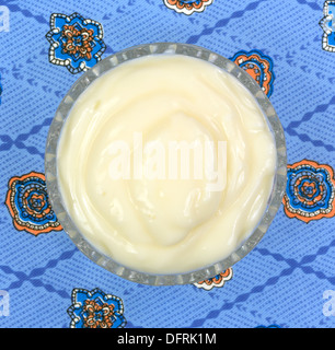 A small glass bowl filled with Boston cream pie flavored yogurt on a colorful blue pattern tablecloth. Stock Photo