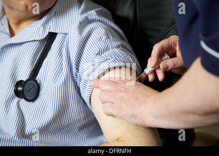 Nurse prepares to give the flu jab injection to a Doctor GP.