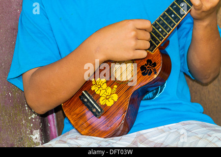 Local boy plays his ukulele. Kosrae, Micronesia Stock Photo