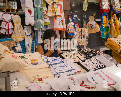 Portugal Algarve Loule market wrinkled elderly middle-aged grey gray haired lady sewing handicraft arts craft stall apron aprons embroidery lace Stock Photo