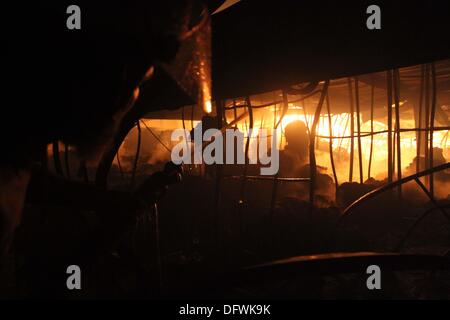 Firefighters try to control a fire inside a garment factory in the Bangladeshi town of Gazipur, 40 km (25 miles) north of the capital Dhaka October 9, 2013. Nine employees including three company managers died in the blaze that originated in the knitting section of Aswad Composite Mills factory, a sister concern of Paul Mall Group. About 50 workers were injured in the fire, whose cause had yet to be determined. Stock Photo