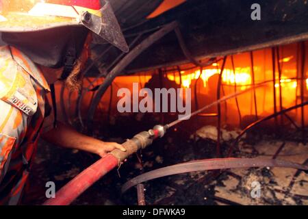 Firefighters try to control a fire inside a garment factory in the Bangladeshi town of Gazipur, 40 km (25 miles) north of the capital Dhaka October 9, 2013. Nine employees including three company managers died in the blaze that originated in the knitting section of Aswad Composite Mills factory, a sister concern of Paul Mall Group. About 50 workers were injured in the fire, whose cause had yet to be determined. Stock Photo