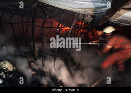 Firefighters try to control a fire inside a garment factory in the Bangladeshi town of Gazipur, 40 km (25 miles) north of the capital Dhaka October 9, 2013. Nine employees including three company managers died in the blaze that originated in the knitting section of Aswad Composite Mills factory, a sister concern of Paul Mall Group. About 50 workers were injured in the fire, whose cause had yet to be determined. Stock Photo