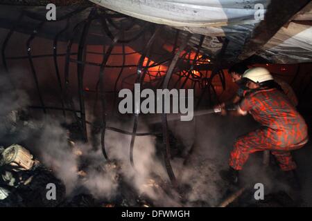 Firefighters try to control a fire inside a garment factory in the Bangladeshi town of Gazipur, 40 km (25 miles) north of the capital Dhaka October 9, 2013. Nine employees including three company managers died in the blaze that originated in the knitting section of Aswad Composite Mills factory, a sister concern of Paul Mall Group. About 50 workers were injured in the fire, whose cause had yet to be determined. Stock Photo