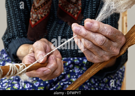 The hands of the elderly woman spinning a wool. Stock Photo