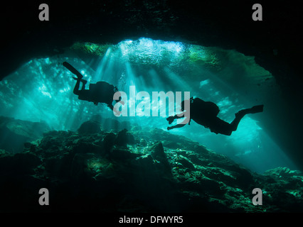 Two divers silhouetted in light at entrance to Chac Mool cenote, Mexico. Stock Photo