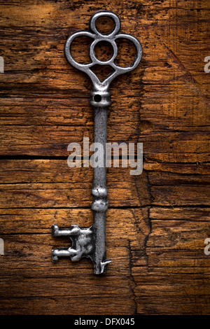 Old ornate skeleton key on rough wood background Stock Photo