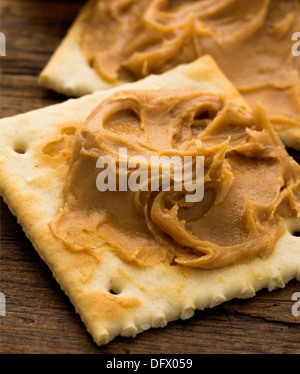 Peanut butter on crackers on weathered plank Stock Photo