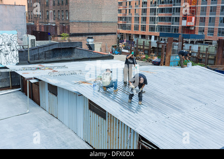 Workers working / painting on a roof in NYC Stock Photo