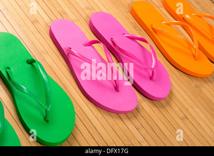 Green, pink and orange flip flop sandals on bamboo mat in closeup Stock Photo