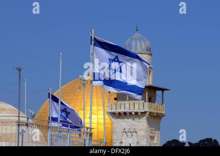View of an Israelian flag on a rooftop in front of the Dome of the Rock and a mosque in the old city of Jerusalem, Israel, 10 September 2013. Jerusalem is a holy city to all three monotheistic religions; Jews, Muslims, and Christians have some of their sanctuaries here. The Dome of the Rock on the Temple Mount is a octagonal building from Umayyad Era. It covers the rock from which, according to Muslim tradition, Muhammad ascended to heaven and met the former prophet of Judaism and Jesus. According to the Biblical tradition, this is the place where Abraham wanted to sacrifice his son Isaac. The Stock Photo
