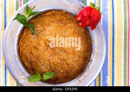 Turkish dessert kunefe isolated on a picnic cloth with mints and sliced strawberry Stock Photo