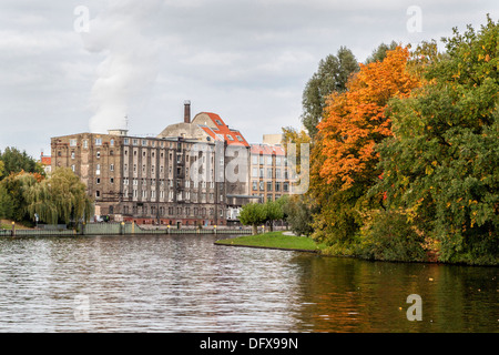 Autumn in Berlin - an old brick factory building and trees with autumnal leaves next to the river Spree Stock Photo