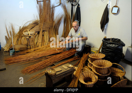 A basket weaver at work in the factory shop in Camacha Madeira Portugal Stock Photo