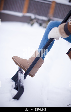 Women's feet at winter boots on snow shovel Stock Photo
