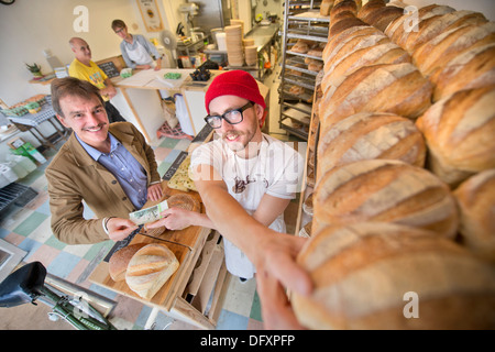 Feature on the Bristol Pound - The East Bristol Bakery, Owner and Head Baker Alex Poulter serves a customer Aug 2013 Stock Photo