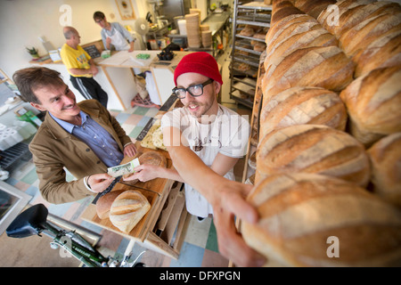 Feature on the Bristol Pound - The East Bristol Bakery, Owner and Head Baker Alex Poulter serves a customer Aug 2013 Stock Photo