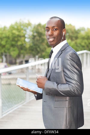 Portrait of a smiling businessman on the phone with hands-free headset and using electronic tablet Stock Photo