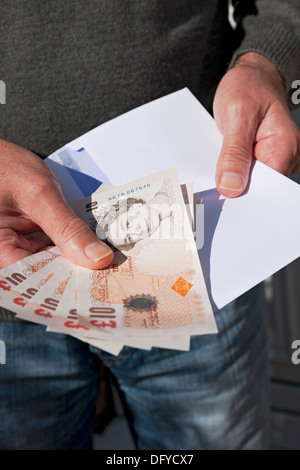 Close up of Man person holding English money cash banknote £10 banknotes ten pound notes and white envelope England UK United Kingdom GB Great Britain Stock Photo