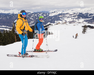 Two male skiers skiing in flat light on red run Marmotte in Le Grand Massif ski area of French Alps above Samoëns resort, France Stock Photo