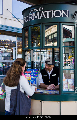 Female tourist making enquiries at tourist information booth at Pike Place Market. Seattle, Washington, USA. Stock Photo